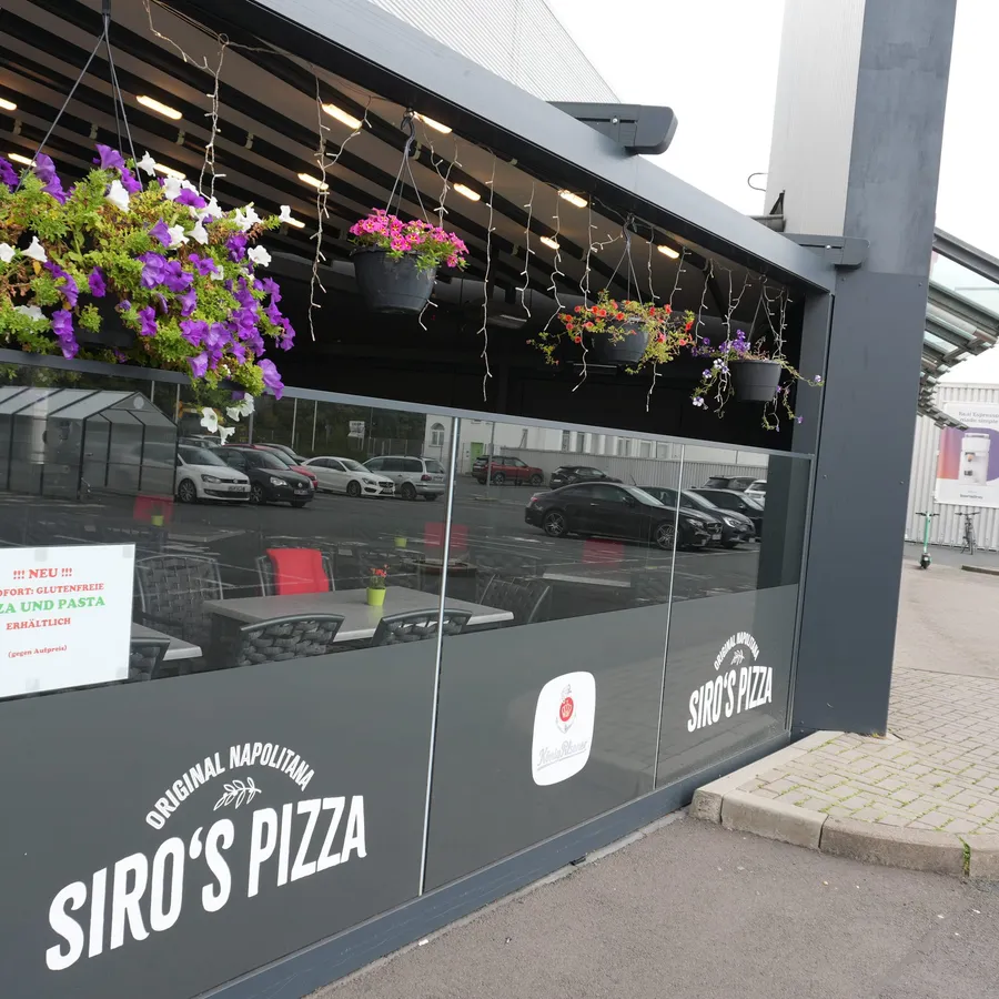 Seitliche Terrasse mit violetten Blumen und Siro’s-Schriftzug